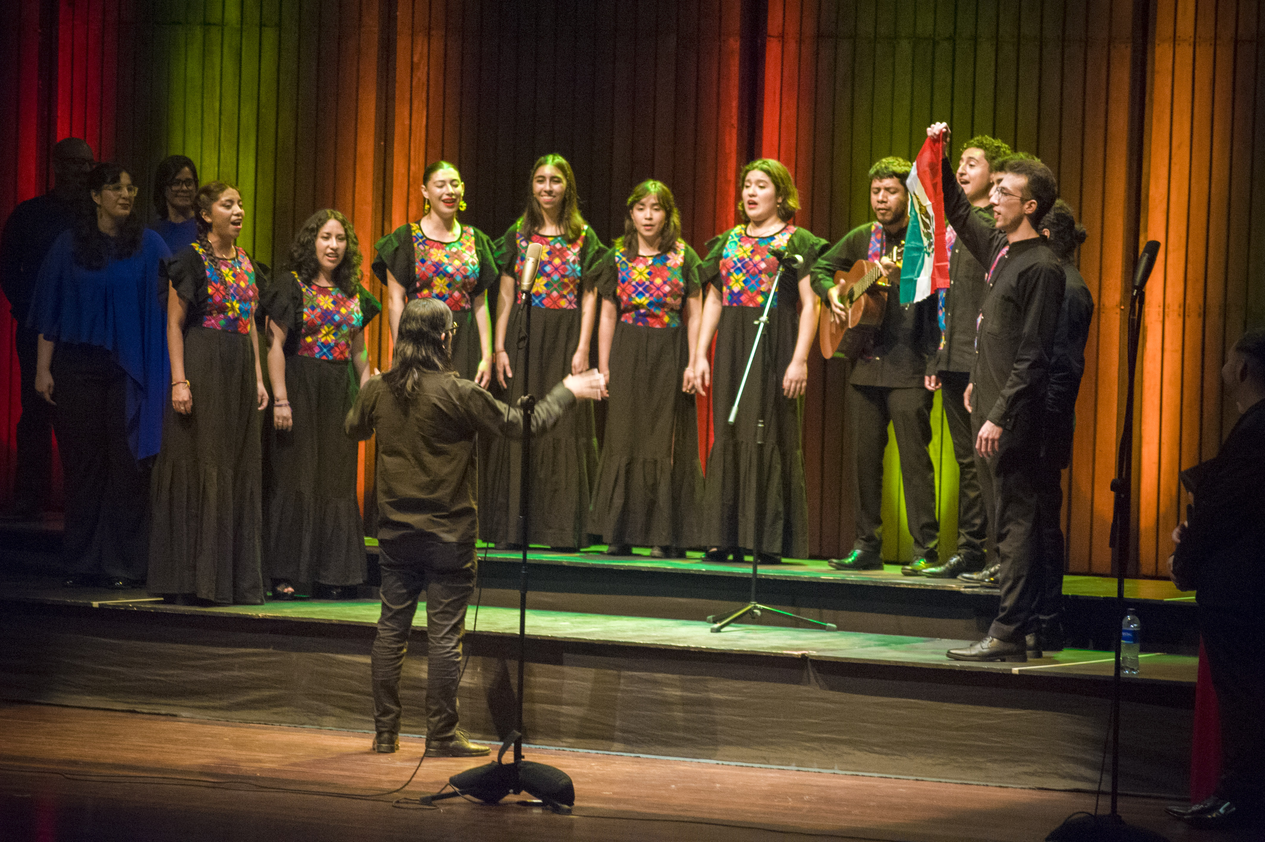 Coro actuando en un escenario iluminado.
